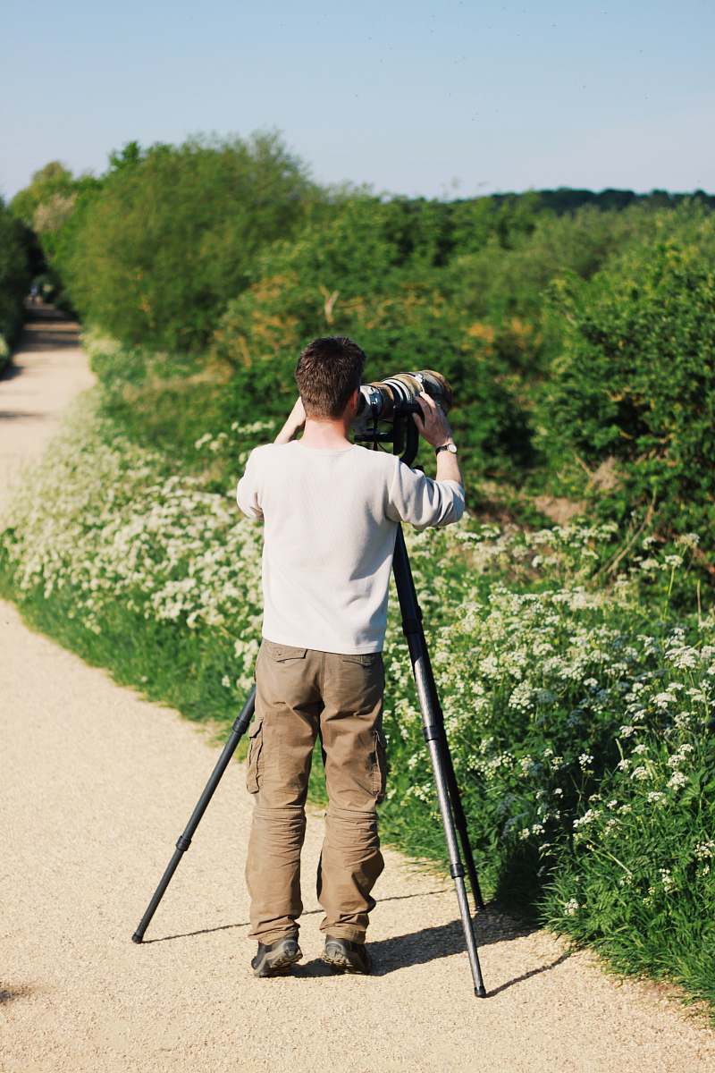 human man in white sweatshirt holding camera tripod
