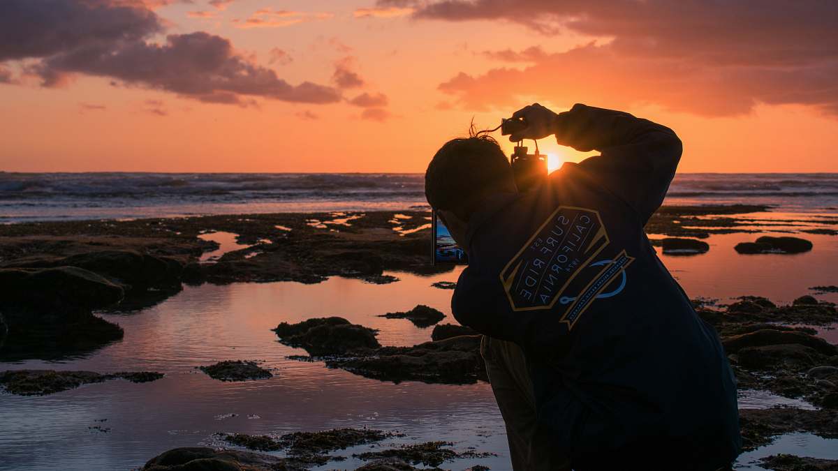 human man standing beside sea during sunset outdoors