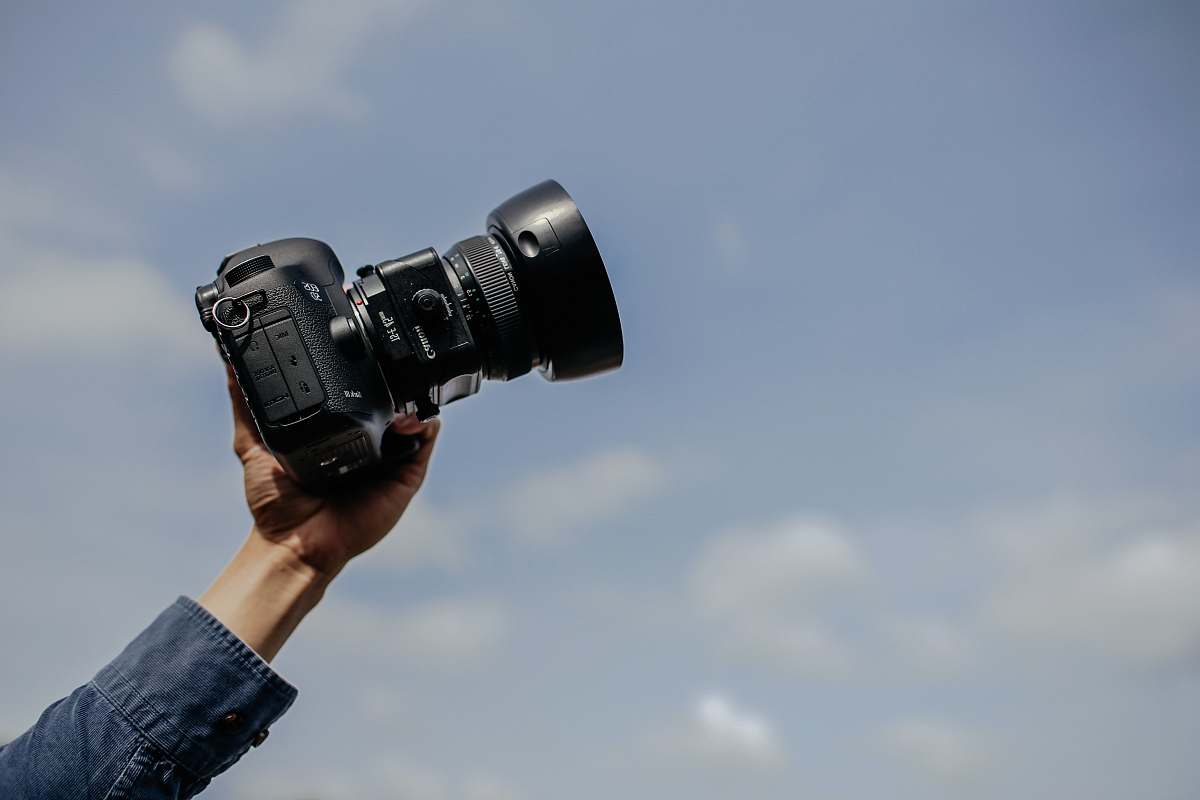 human man using his black DSLR camera electronics
