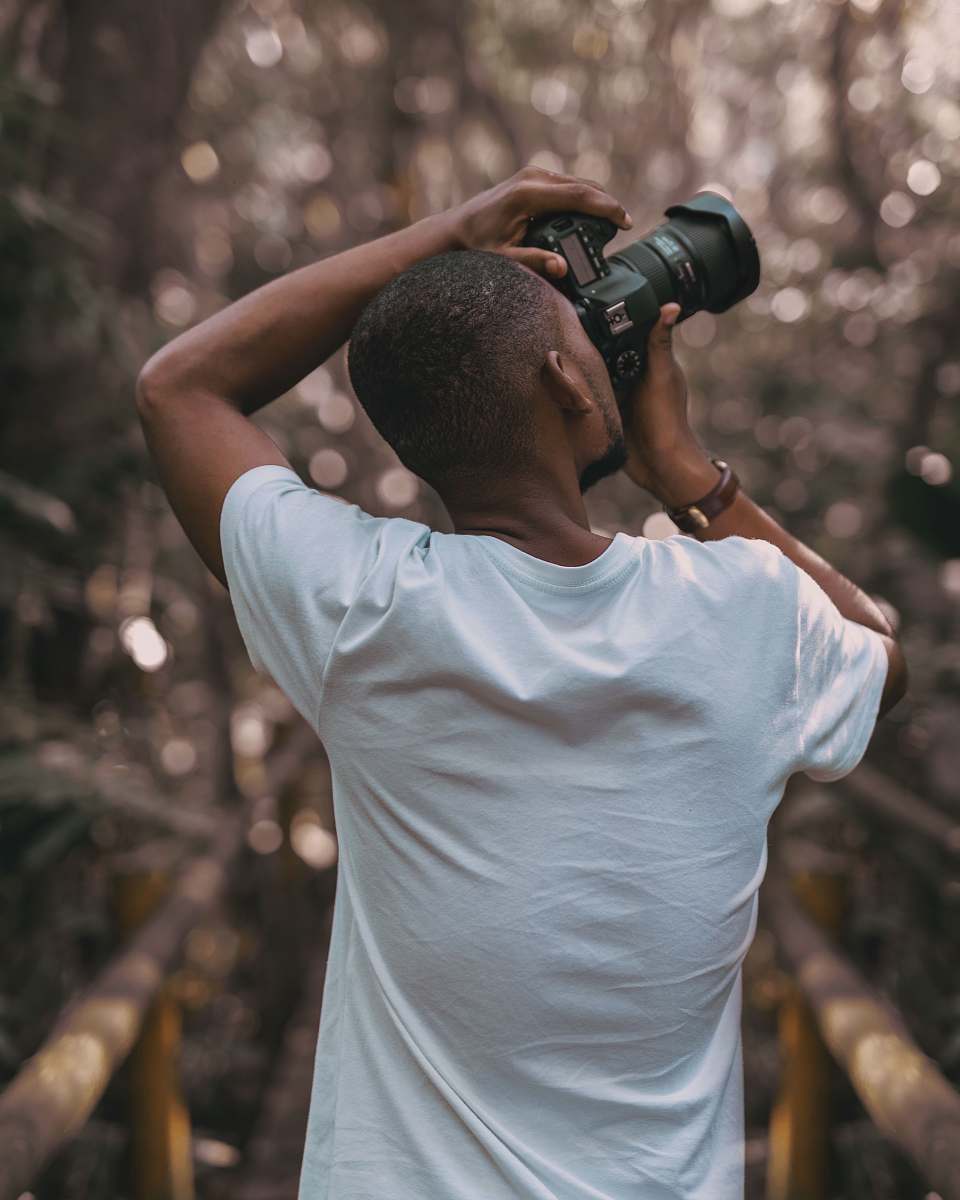 human selective focus photography of a man in white t-shirt using a DSLR camera photographer