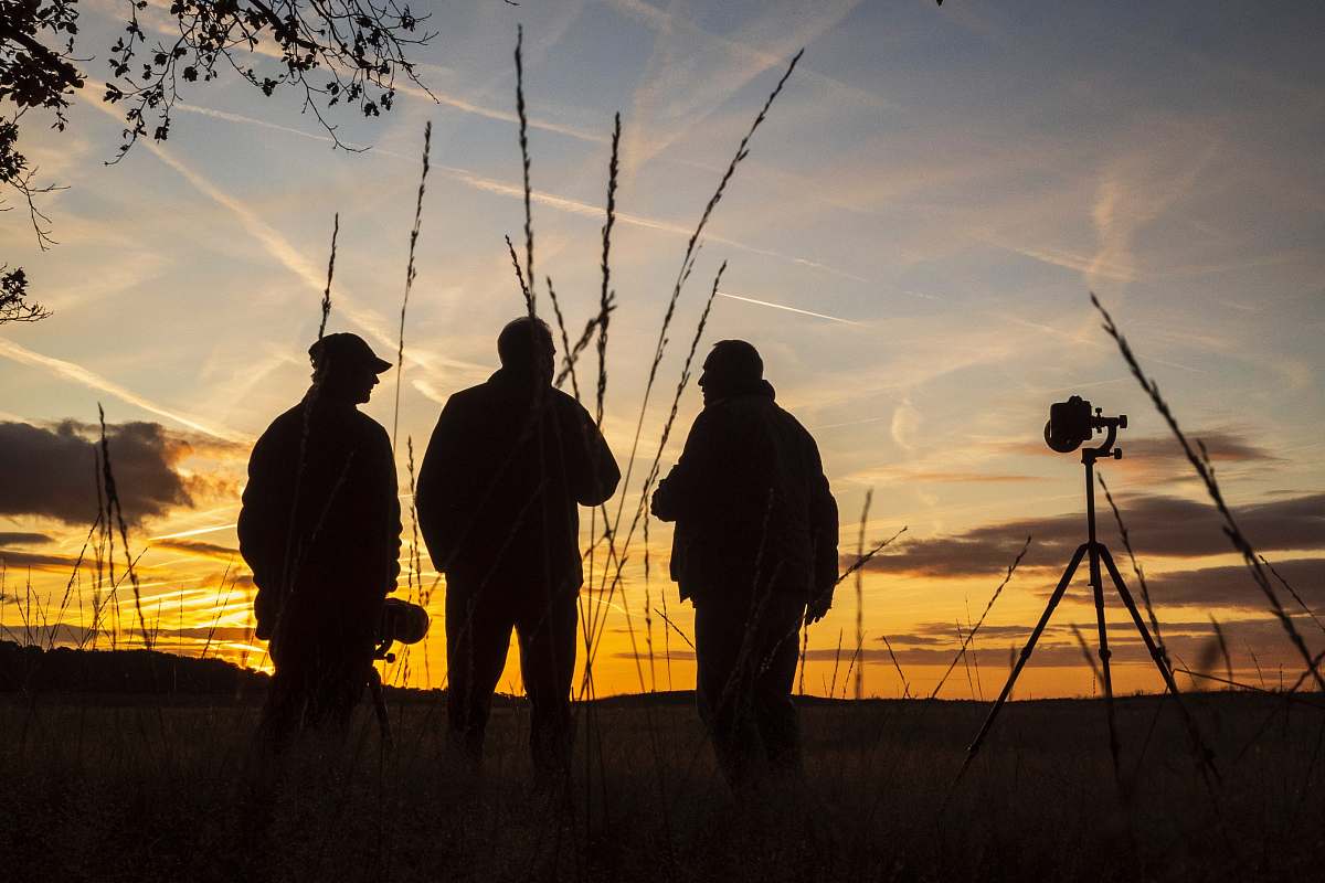 human silhouette of 3 men standing besides camera silhouette