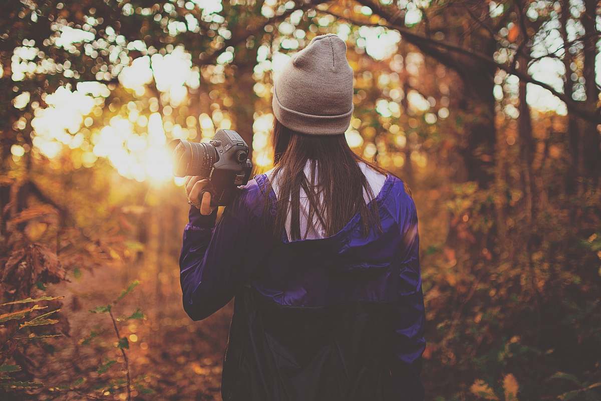 girl woman in forest holding DSLR camera during golden hour human