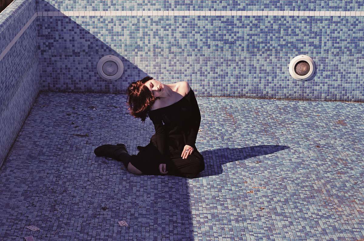 human woman sitting inside the empty pool black
