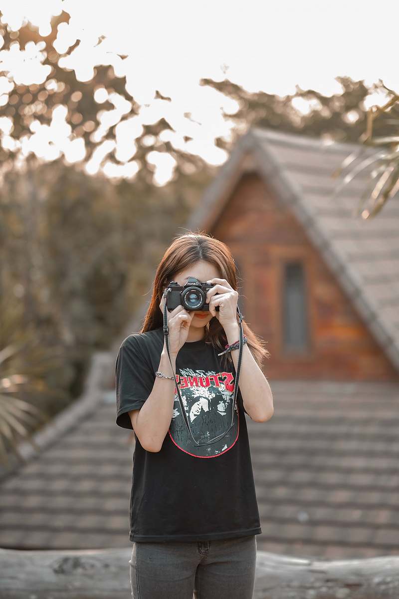 human woman standing and using DSLR camera photo