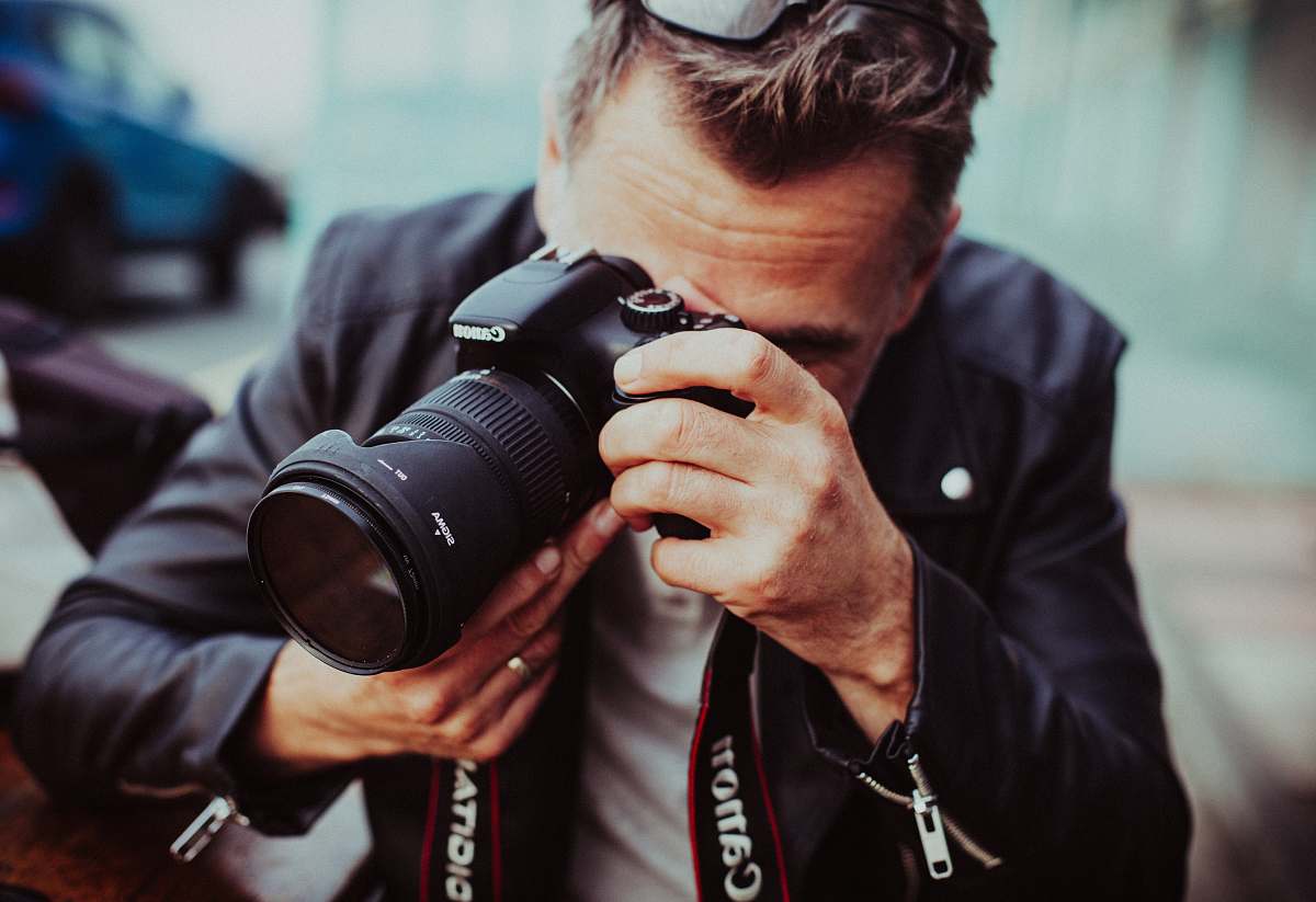 man man holding up Canon DSLR camera male