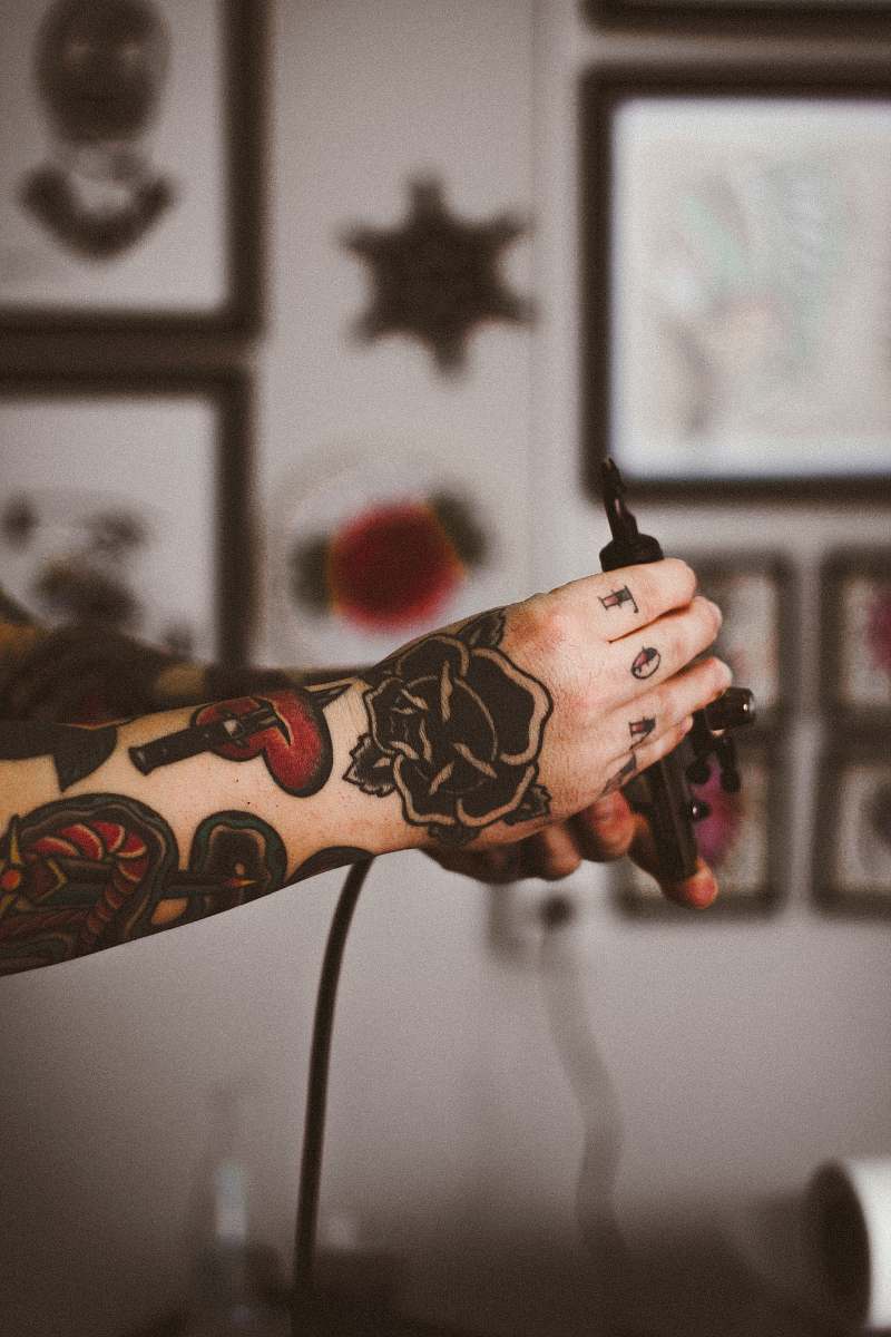 hands shallow focus photography of person holding black tattoo machine ornament