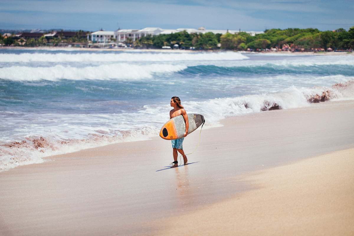 sea man carrying yellow and white surfboard standing near beach surfboard