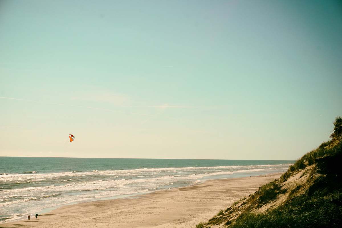 water person flying kite on seashore ocean
