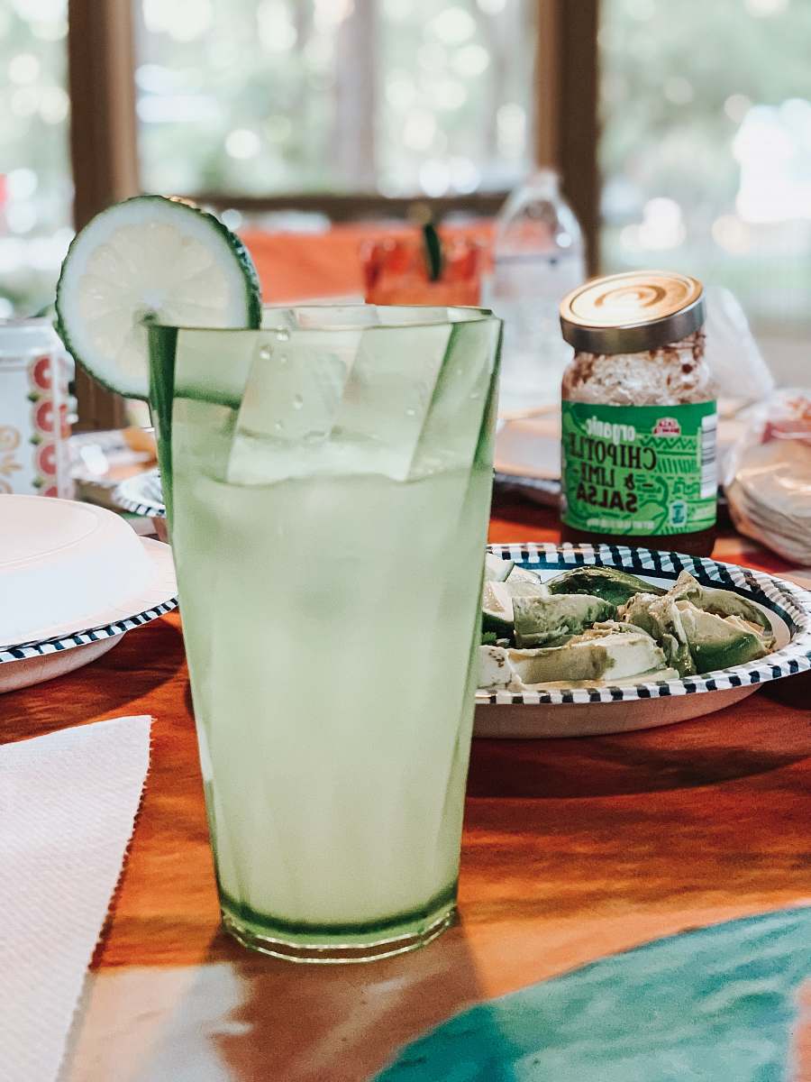 drink lime juice with sliced lime on top near food in plate beside organic chipotle and lime salsa jar on table lemonade