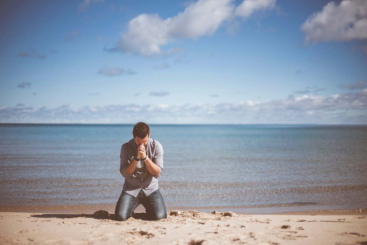 person man kneeling down near shore beach