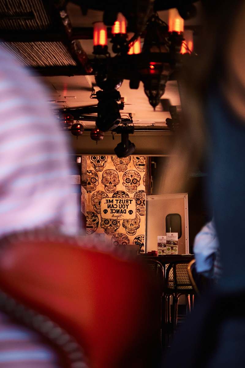 This captivating image showcases a woman seated comfortably in a stylish restaurant, holding a camera as she prepares to capture the perfect moment. The ambiance of the eatery, with its elegant decor and inviting atmosphere, sets the stage for memorable interactions and delightful experiences. Ideal for use in articles about dining, photography, or lifestyle, this photo perfectly illustrates the fusion of gastronomy and creativity.