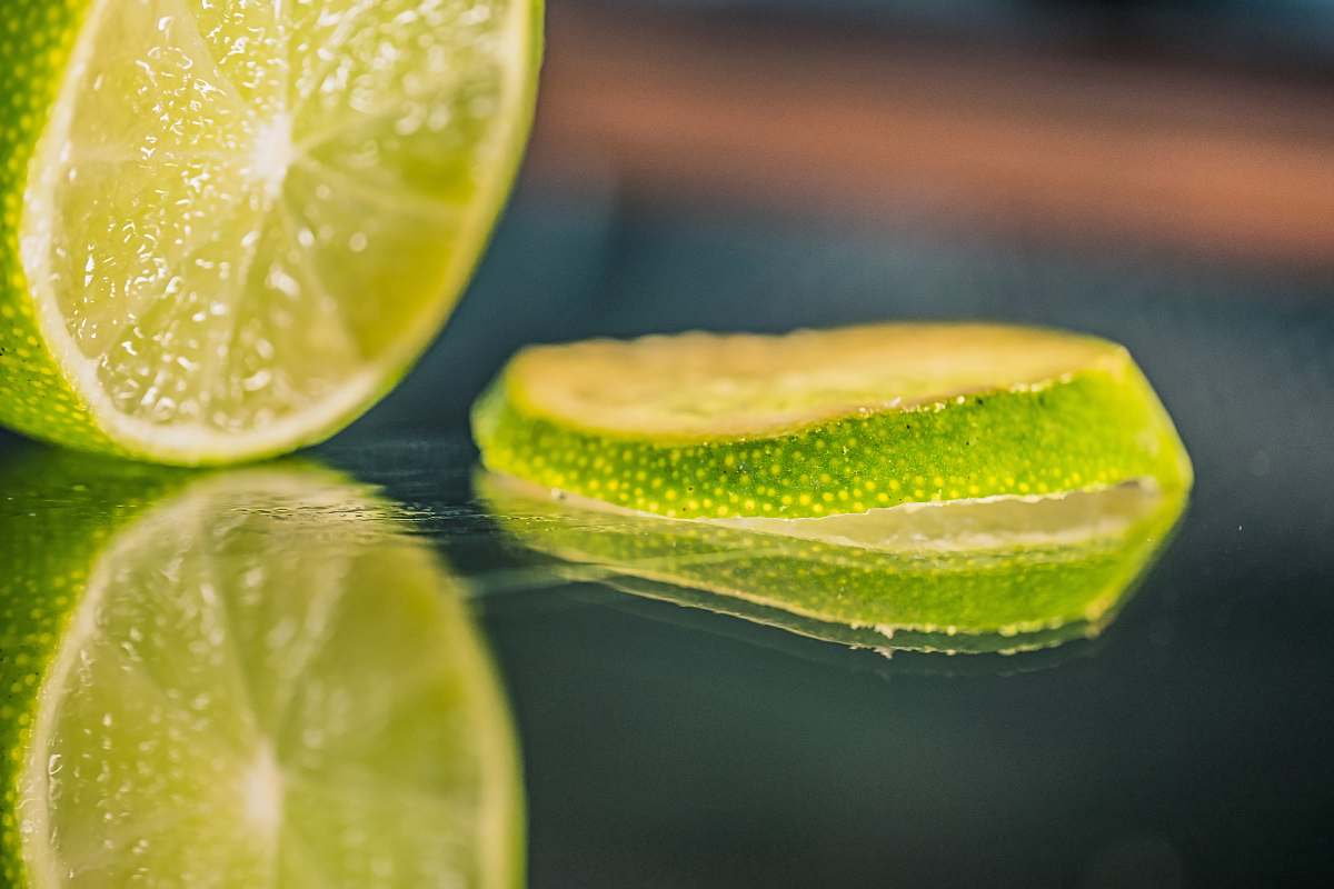 food green lemon on water during daytime citrus fruit