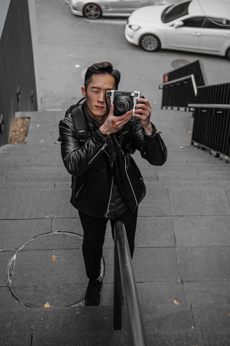 clothing shallow focus photo of man in black leather jacket using camera coat