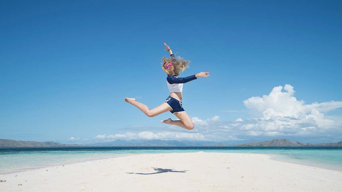 sea woman jumping with raising her right hand sand