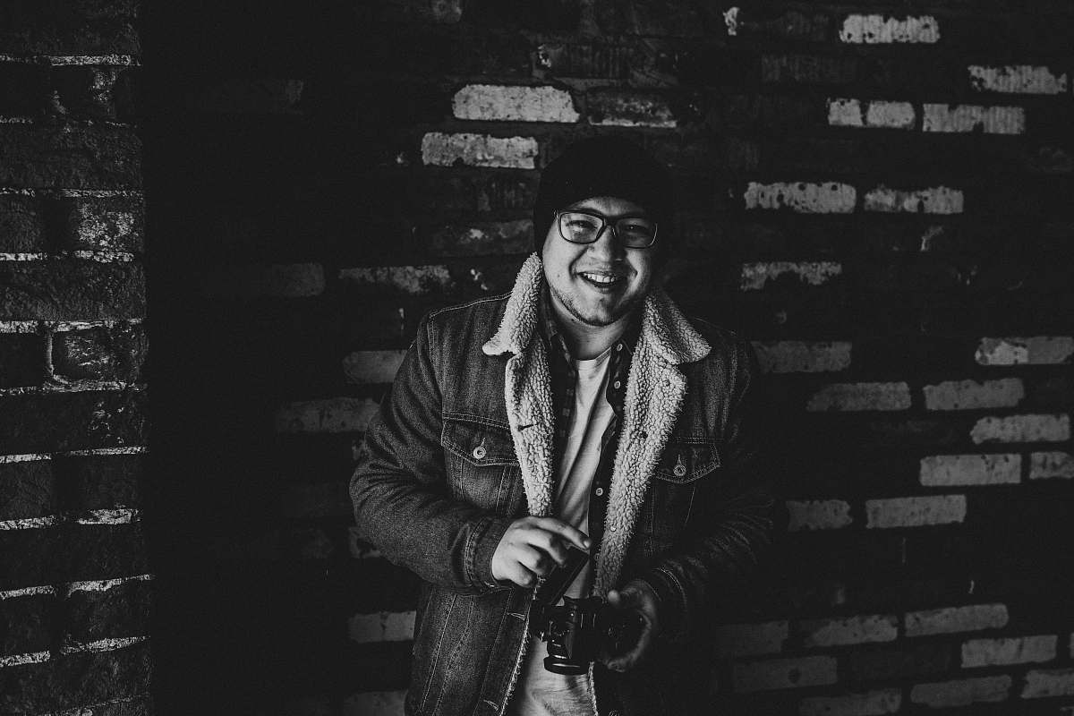 apparel grayscale photography of smiling man carrying camera clothing