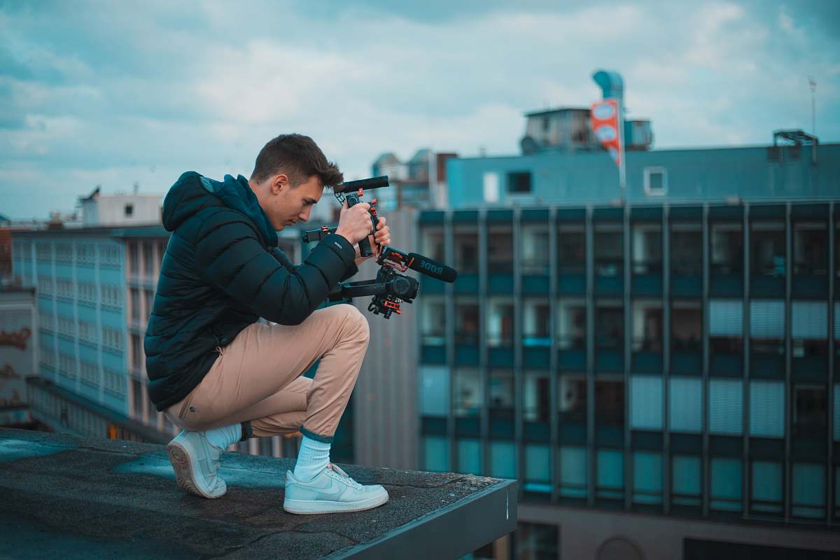 footwear man in black bubble jacket kneeling on top of the building during daytime shoe