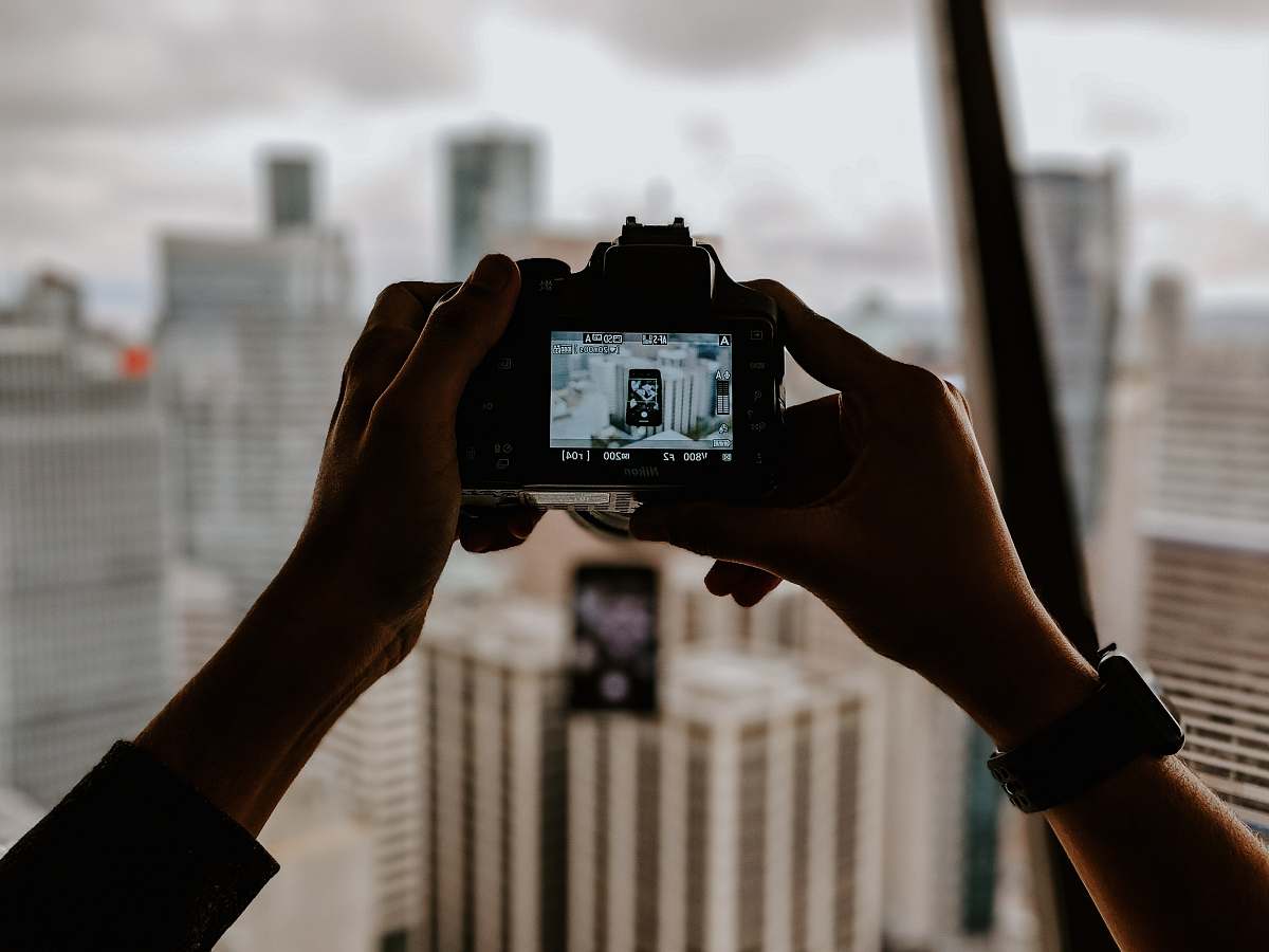 person focus photography of DSLR camera talking photo of buildings camera
