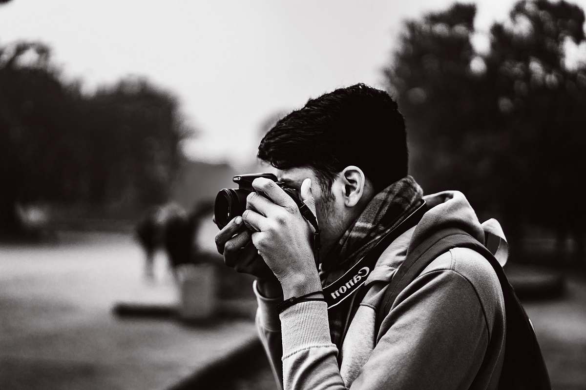 person grayscale photography of man taking photo using camera camera