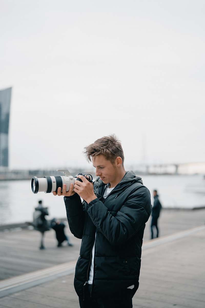 person man holding black DSLR camera outdoors photographer