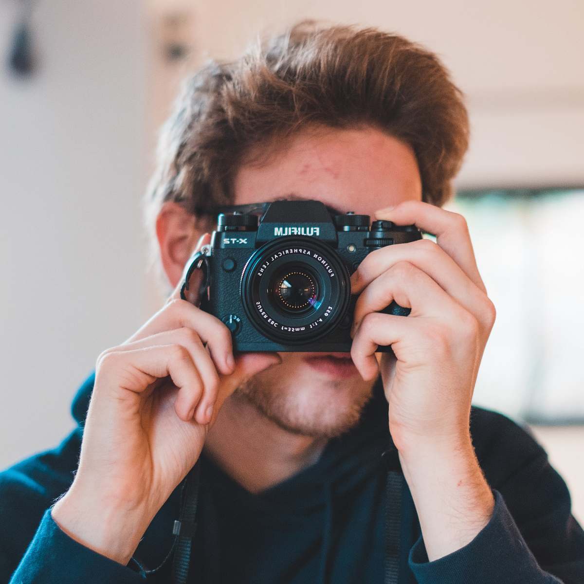 person man holding black Fujifilm camera taking picture camera