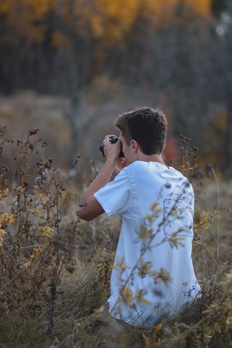 person man holding camera on brown grass field photo