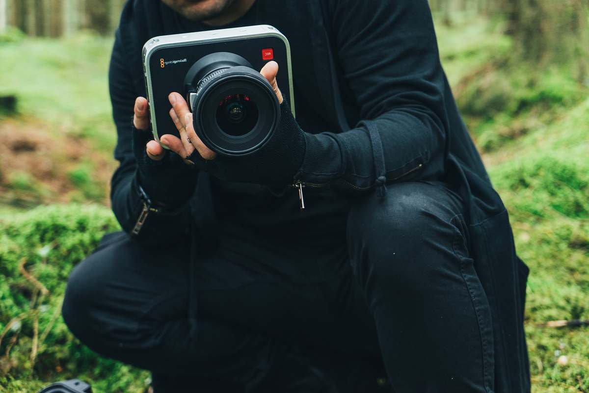 electronics man in black jacket holding DSLR camera camera