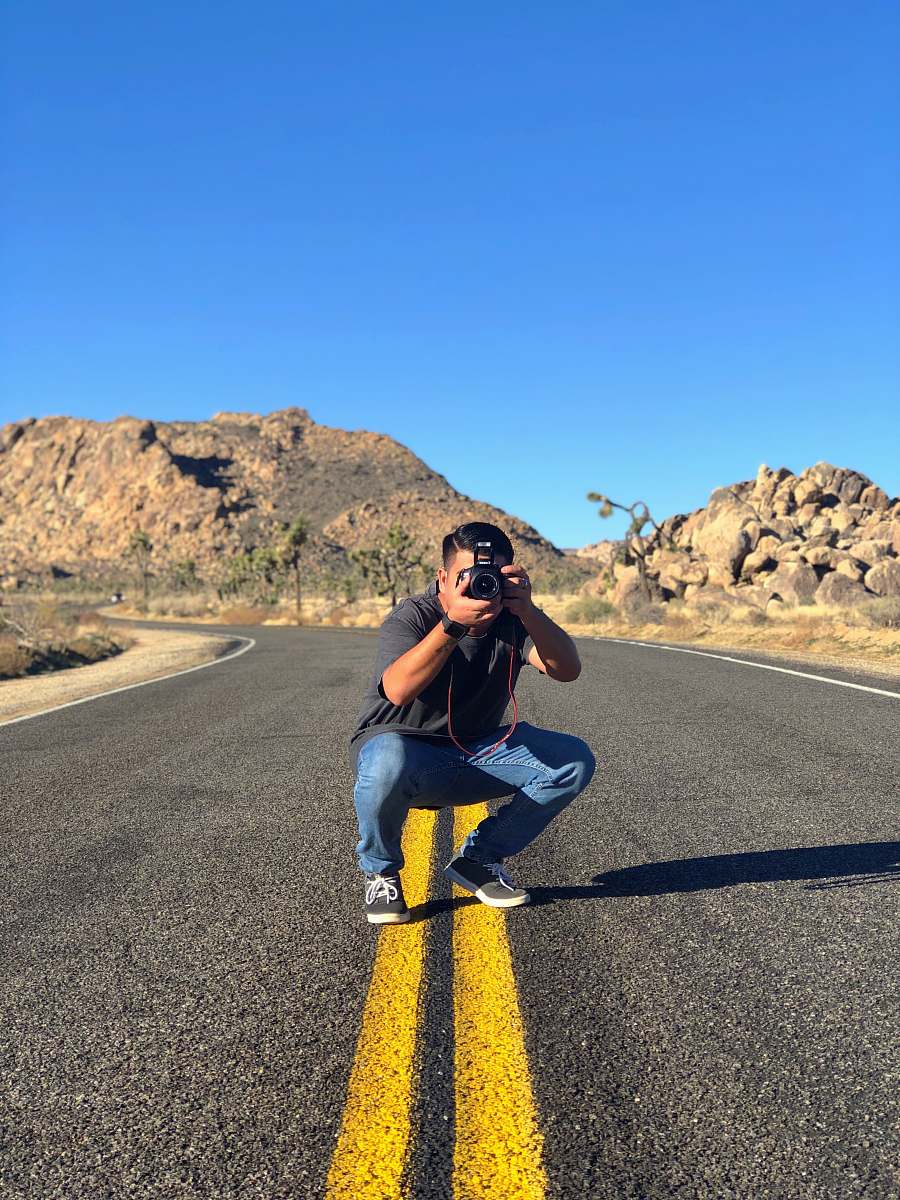 person man sitting in road taking picture asphalt