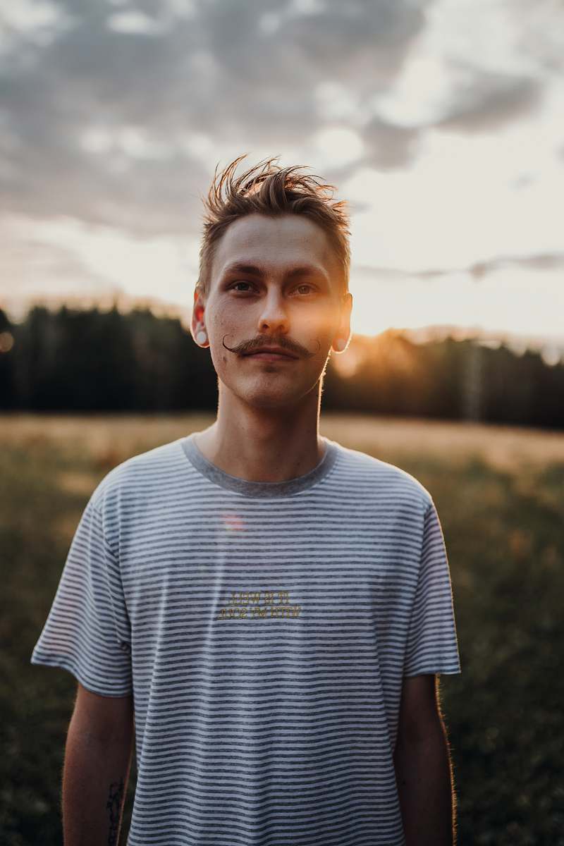 person man standing on grass and in front of trees man