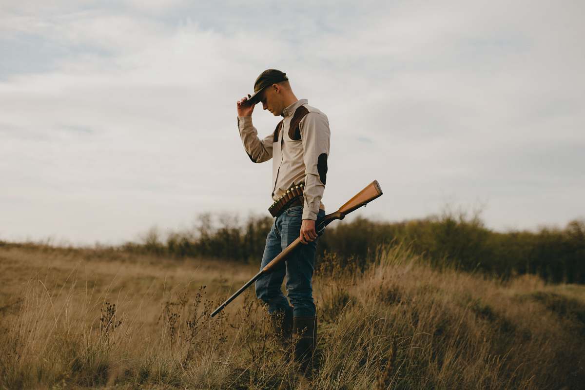 Person Man Standing While Holding Shotgun Photo Image Free Photo