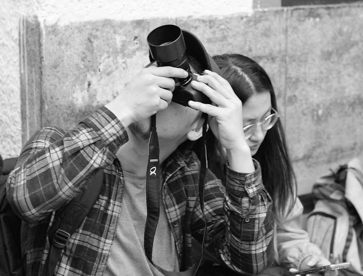 person man taking photo above sitting beside woman black-and-white
