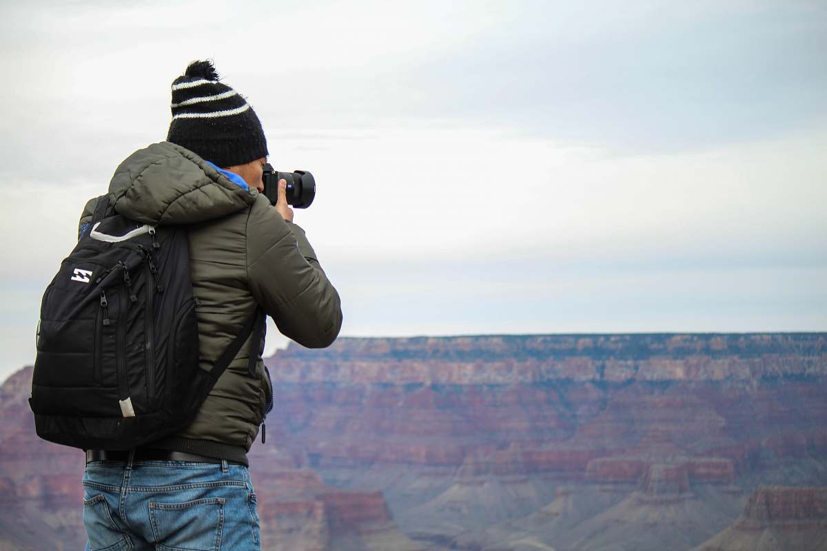 person man taking photo of rock formation outdoors