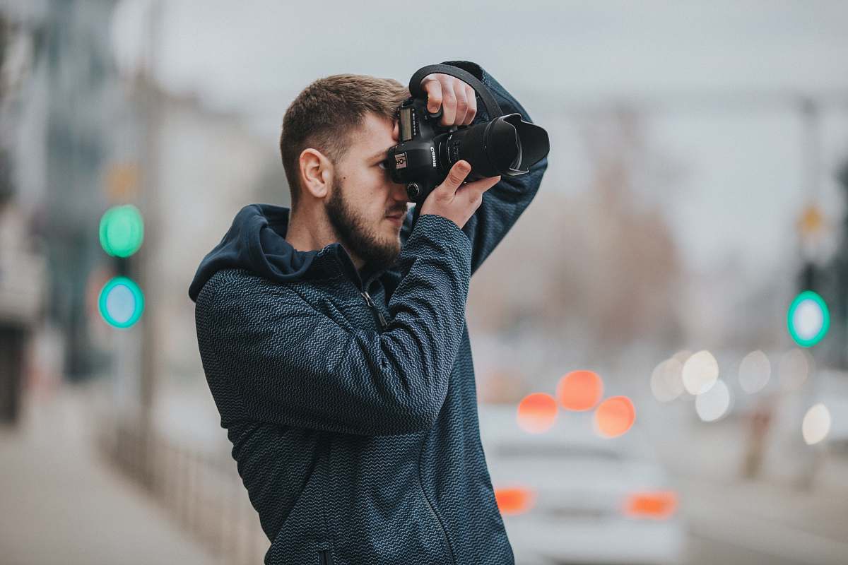 person man wearing black hoodie using DSLR camera shooting pictures photographer