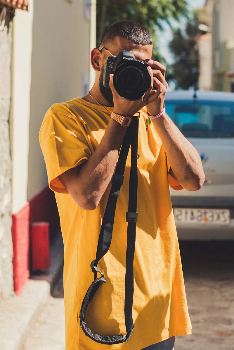 camera person holding black DSLR camera electronics