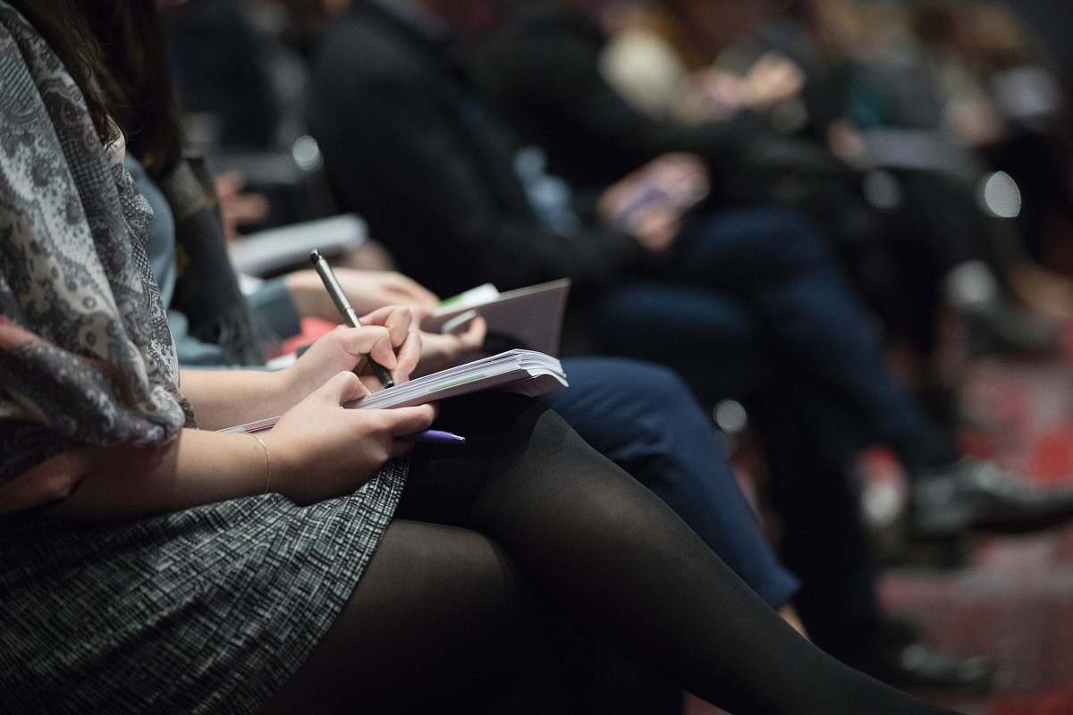 person selective focus photography of people sitting on chairs while writing on notebooks people