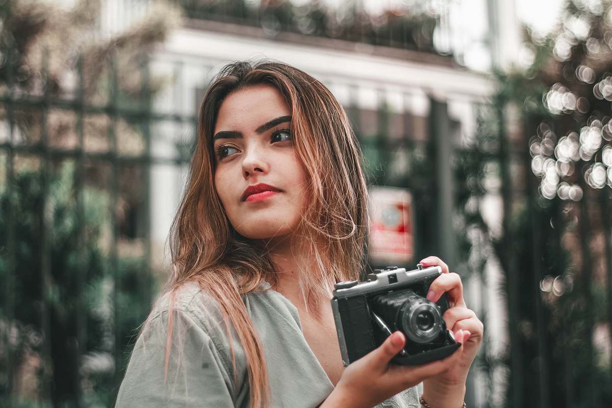 person selective focus photography of woman wearing gray top holding camera camera