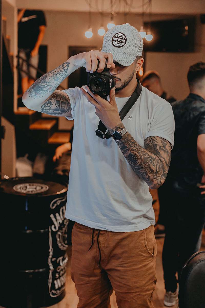 person shallow focus photo of man in white crew-neck T-shirt using black point-and-shoot camera skin