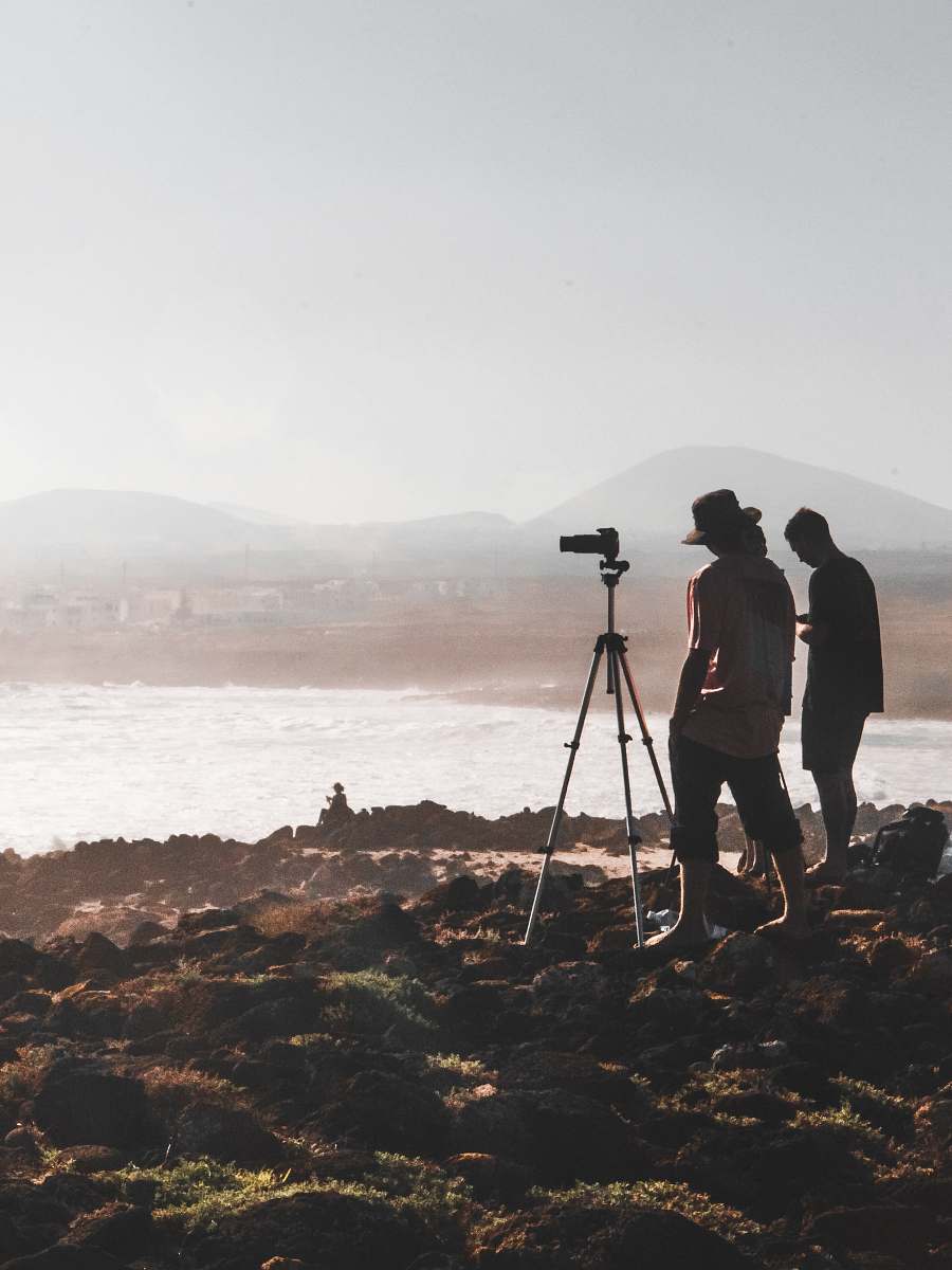 person two person standing in front of camera across mountain tripod