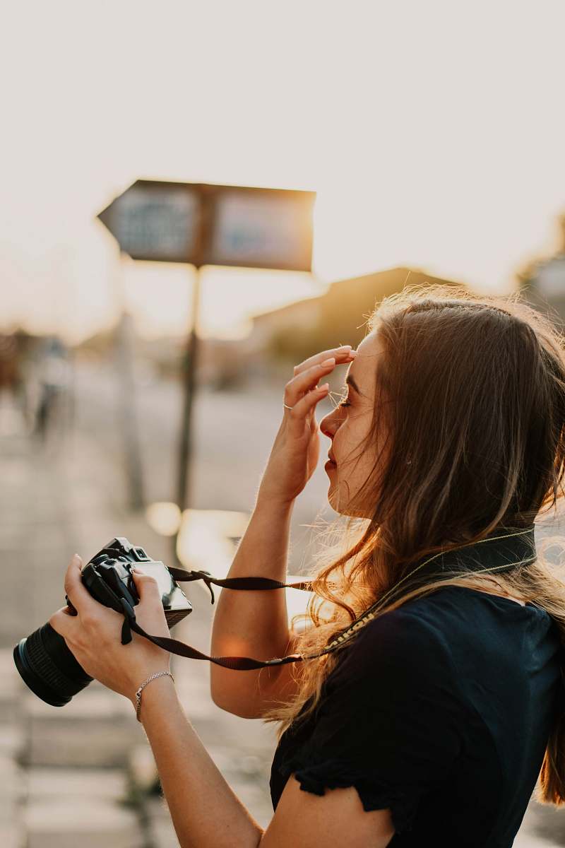 person woman in black shirt holding DSLR camera photographer