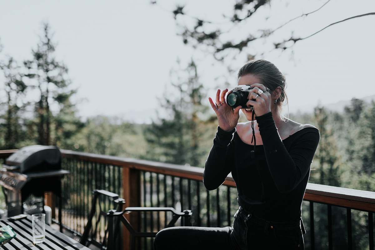 person woman sitting beside balustrade taking photo electronics