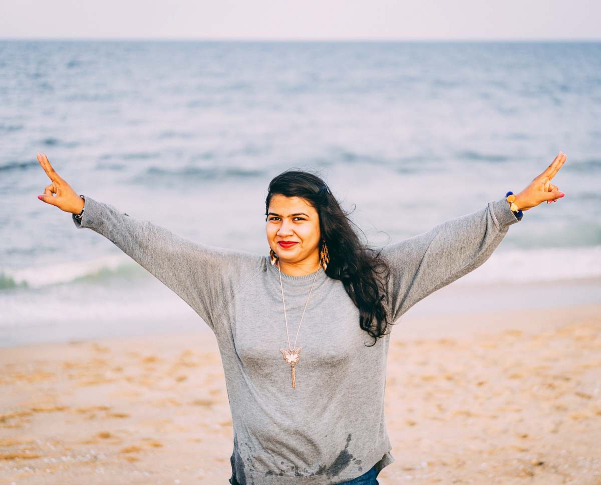 person woman standing and spreading her arms on seashore face