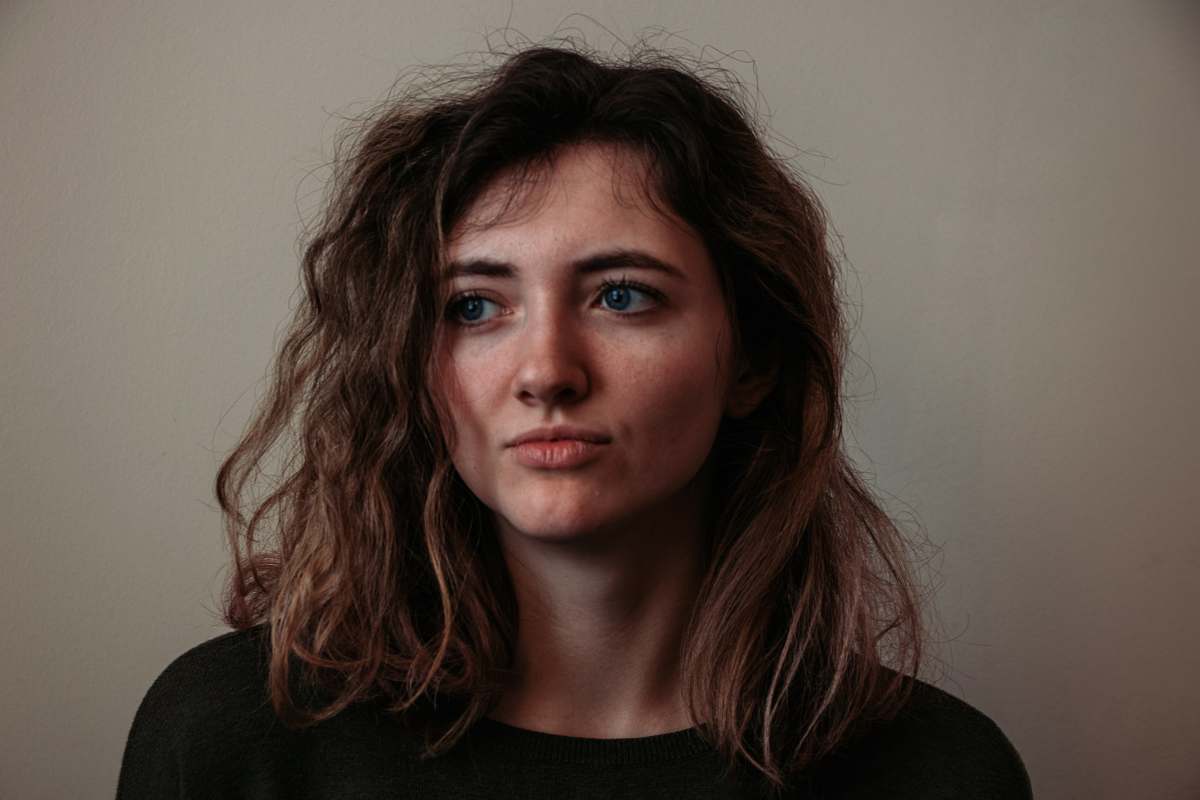 person woman standing beside wall face