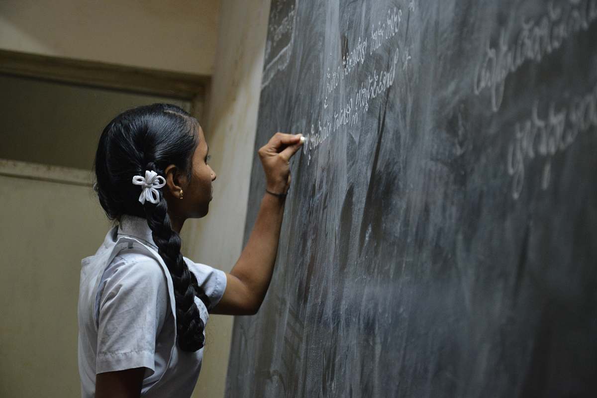 person woman standing writing on black chalkboard people