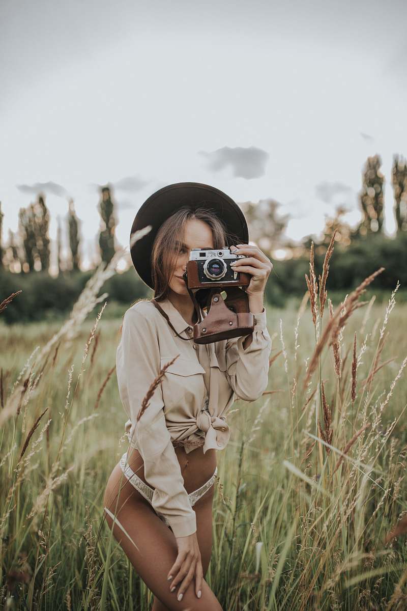 person woman wearing white pantie holding gray and brown camera plant