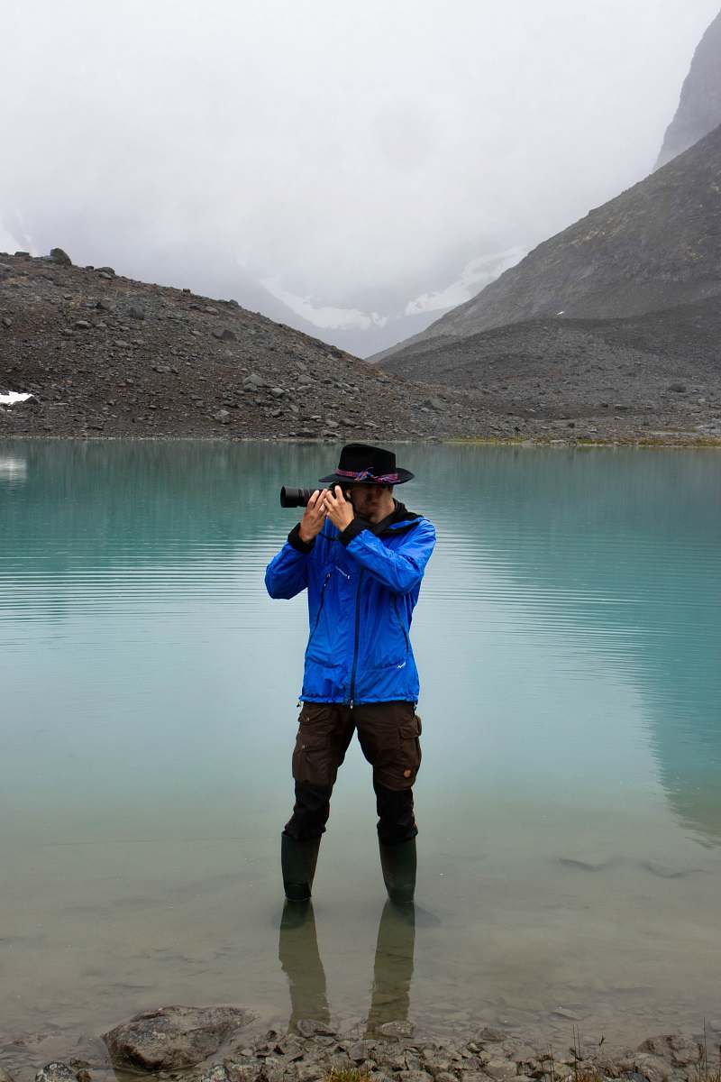 human man standing on body of water using DSLR camera apparel