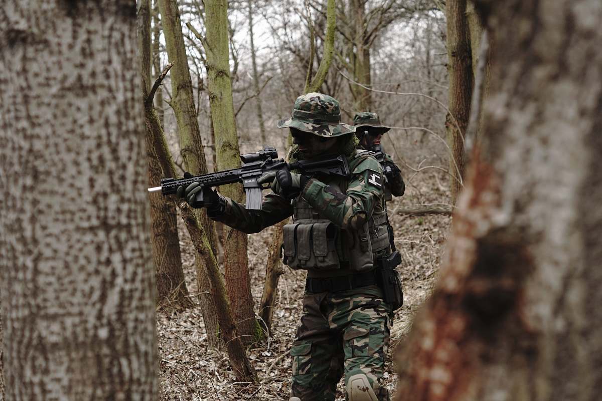 human soldier holding assault rifle in forest military