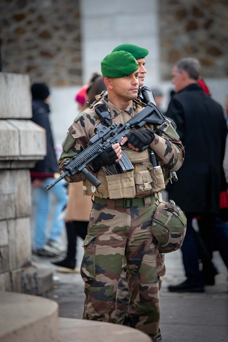 human soldier with rifle stands guard in front of building gun