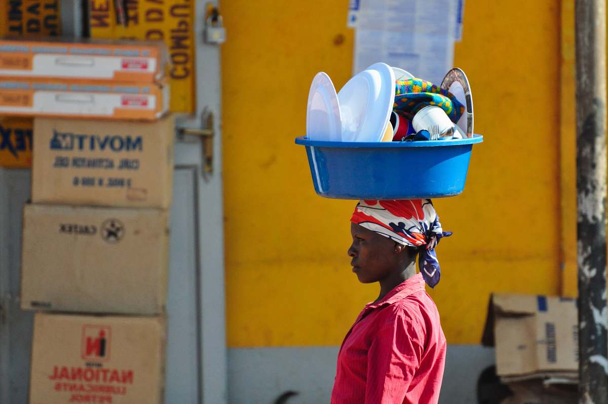 human woman in red collared top carrying basin on head people