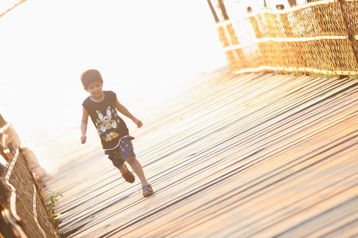 person boy walking on brown wooden bridge people