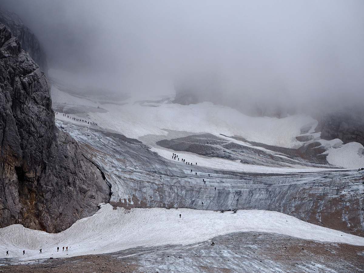snow group of people walking on mountain trail under sea of clouds mountain