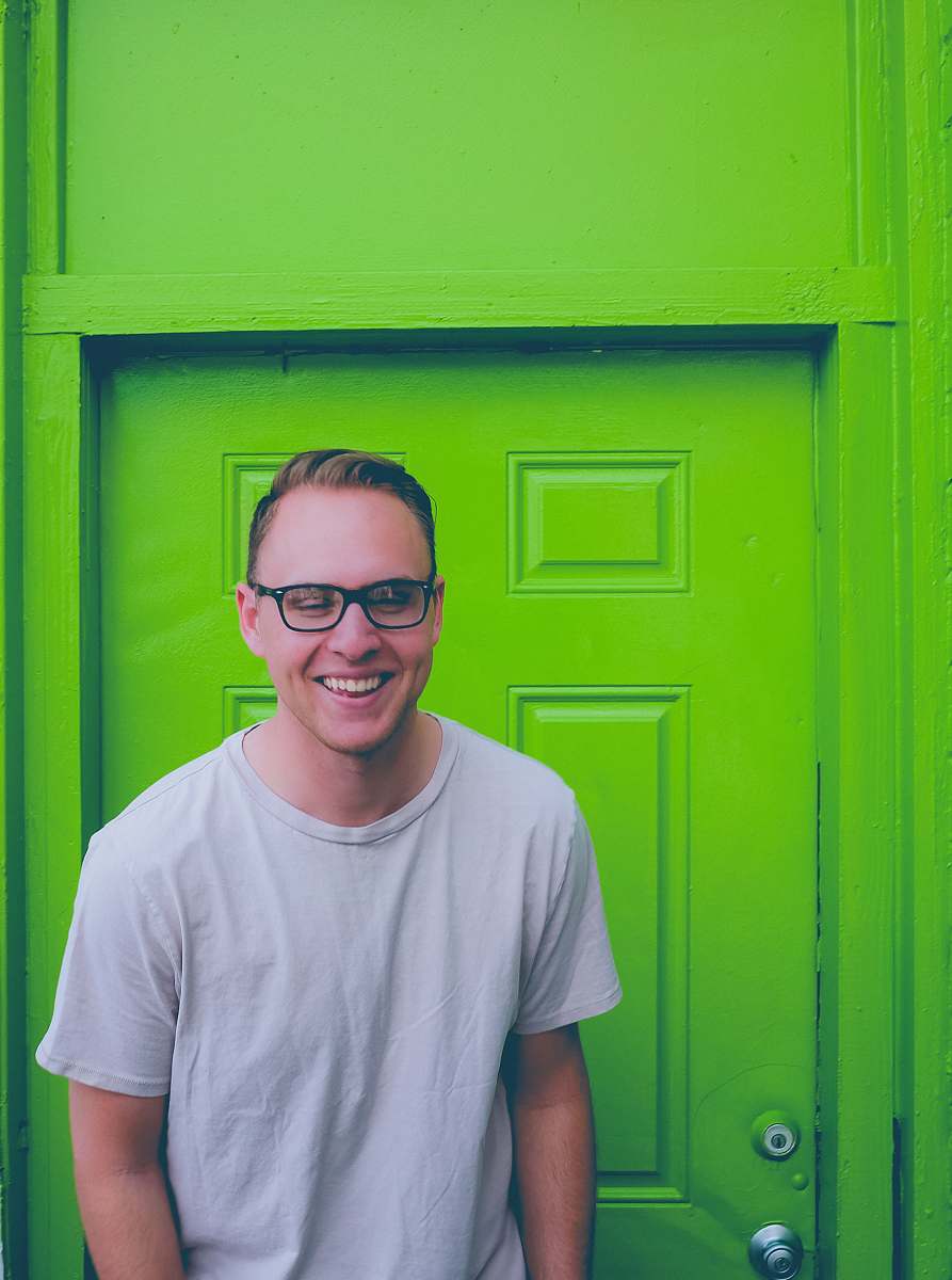 clothing unknown person in white crew-neck top standing near green door apparel
